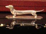 silver dog figurine sitting on top of a table next to a red pillow