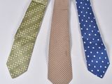 four different colored ties are lined up on a white surface