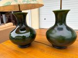 two green vases sitting on a table with a lamp