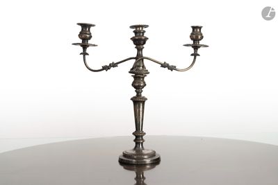 un candélabre en argent avec trois bougies posé sur une table