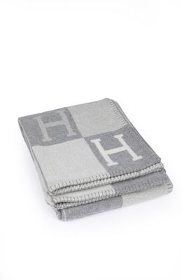 la couverture grise et blanche est pliée sur une surface blanche
