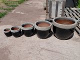 many pots that are sitting on the ground in the yard