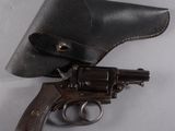 un vieux pistolet dans un étui en cuir posé sur une surface blanche