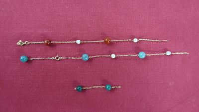 three bracelets of different colors and sizes on a pink surface