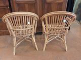 pair of wicker chairs sitting in front of a cabinet in a room