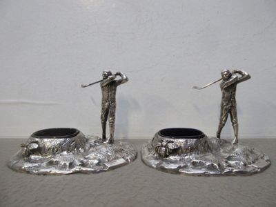 deux figurines en argent représentant un homme et une femme avec des clubs de golf