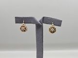 une paire de boucles d'oreilles posée sur un présentoir, sur fond gris