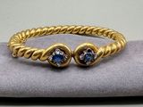 un gros plan d'un bracelet en or orné de deux pierres bleues