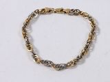a close up of a gold and silver bracelet on a white surface