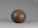 a brown vase sitting on top of a table next to a gray wall