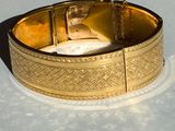 a close up of a gold bracelet on a white surface