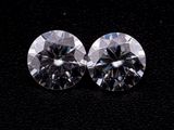 two round cut diamonds on a black surface