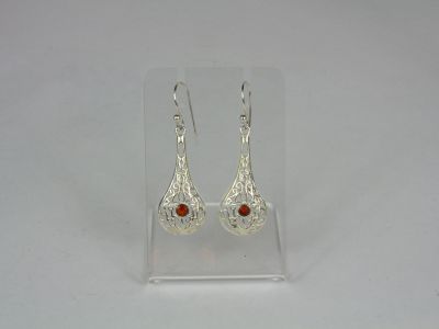 silver earrings with garnets on them on a clear stand