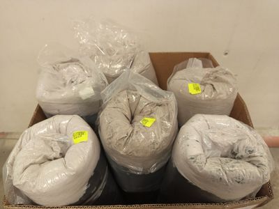 Plusieurs pelotes de fil blanc se trouvent dans une boîte posée par terre.