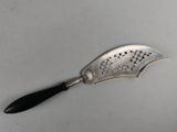 an old silver spoon with a black handle on a white surface