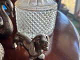 a table with a glass vase and silver figurines on it