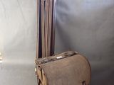 un sac en papier brun posé sur une chaise en bois, à côté d'un trépied
