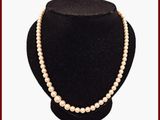 collier de perles présenté sur un mannequin devant un fond rouge