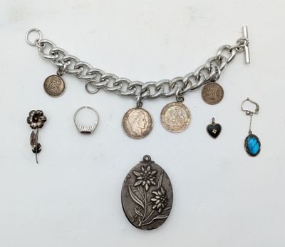 an assortment of silver and silver jewelry including a coin, a necklace, and a bracelet