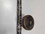 a close up of a metal pipe with a wooden handle on a white wall
