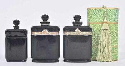 trois bocaux noirs ornés de pompons et une boîte verte posés sur une surface blanche