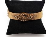 un gros plan sur un oreiller noir sur lequel repose un bracelet doré