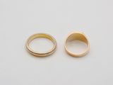 two gold rings on a white surface