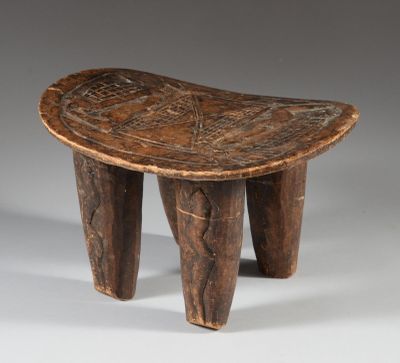 an old wooden stool with carved legs on a grey background