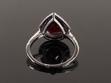 a close up of a ring with a red stone on a black surface
