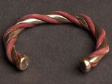 a close up of a red and gold bracelet on a black surface