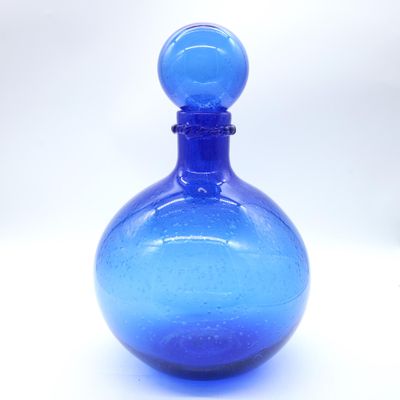 a blue glass bottle sitting on a white surface