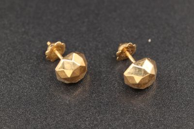 une paire de boucles d'oreilles en or sur une surface noire