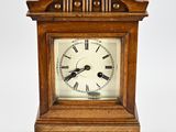 une petite horloge en bois avec des chiffres romains sur le cadran