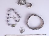 a lot of silver jewelry on a white surface