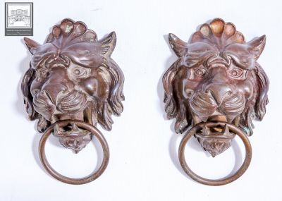 pair of bronze lion head door knockets on a white background