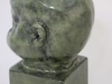 a green sculpture of a head on top of a block