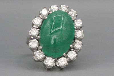 gros plan d'une bague avec une pierre verte entourée de diamants blancs