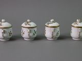 three white porcelain jars with gold trims are lined up on a gray surface