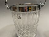 a silver plated ice bucket and a glass cup on a table