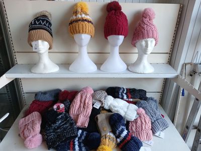 de nombreux bonnets et mitaines posés sur une étagère dans une pièce