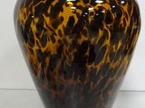 a brown and black vase sitting on a white surface