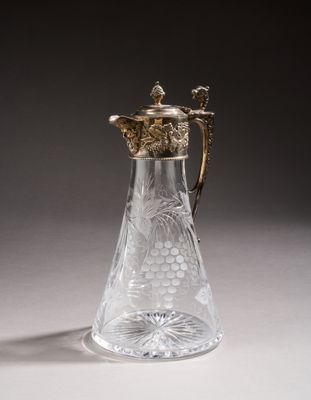 a glass pitcher with a gold handle on a table