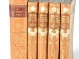 several old books are lined up in a row on a white surface