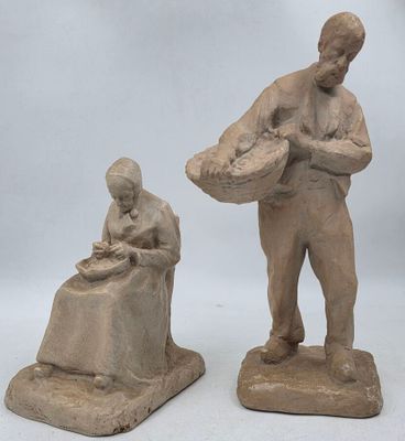 deux sculptures en argile représentant un homme et une femme assis sur un banc