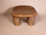 an old wooden stool sitting on top of a white surface