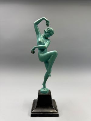 Une statue représentant une femme en robe verte se dresse sur un socle noir.