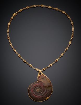un collier en or avec un pendentif en pierre rouge, monté sur une chaîne en or