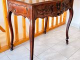 a wooden table with a marble top on a tiled floor
