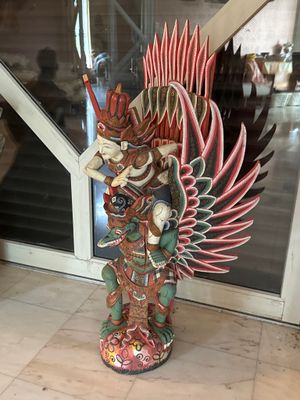 une statue représentant un homme tenant une épée devant une porte vitrée
