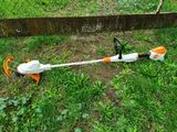 an orange and white string trimmer sitting on top of a lush green field